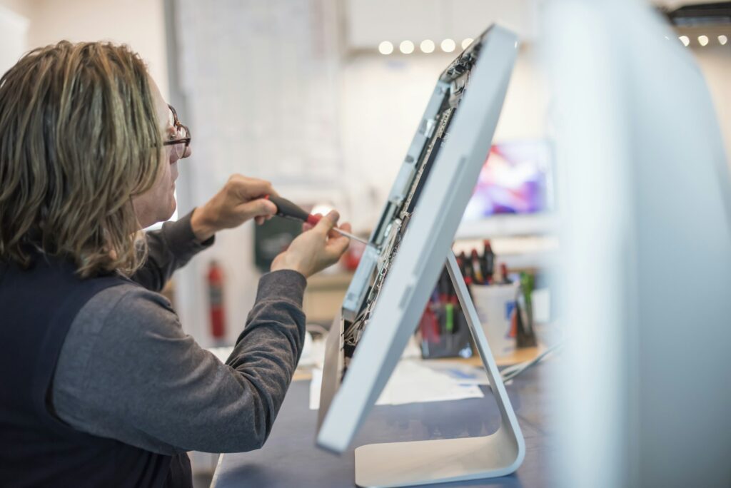 Technician performing panel-level repair on a display monitor